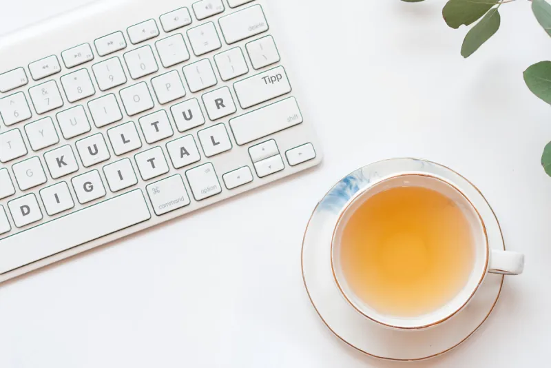 Kulturtipp Digital entdecken: Tastatur mit den Wörtern KULTUR Tipp DIGITAL neben einer Tasse Tee.